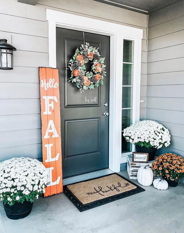Cute front porch featuring a leaning front porch sign, a wreath, a doormat, corn stalks, and pumpkins.