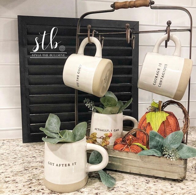 Stylish mug rack for the fall with cute mugs, a few pumpkins, and a black shutter 