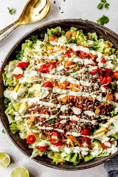 Taco Salad, a beloved main dish, packs juicy beef, crunchy lettuce, fresh veggies, creamy dressing, and crispy tortilla chips in every bite.