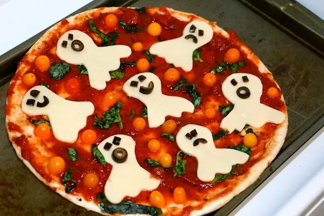 Non-dairy mozzarella slices are cut into cute ghost shapes, complete with olive eyes and mouths for a spooky touch.