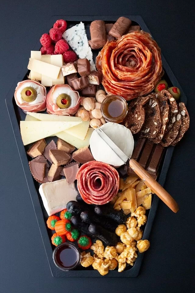 Fill a coffin-shaped tray with cheeses, meats, and Halloween candies.