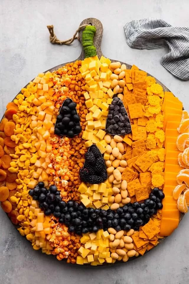 Arrange meats, cheeses, and fruits in the shape of a jack-o’-lantern.