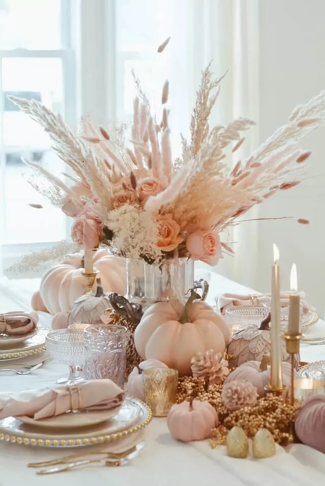 Soft roses, dried florals, and painted pumpkins add gentle color.