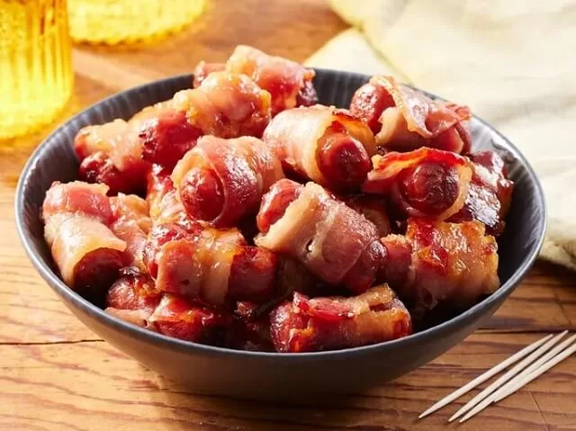 Brown sugar smokies are wrapped in bacon and glazed sweet. Bake them until the bacon is crisp and caramelized. Visit https://sharpaspirant.com