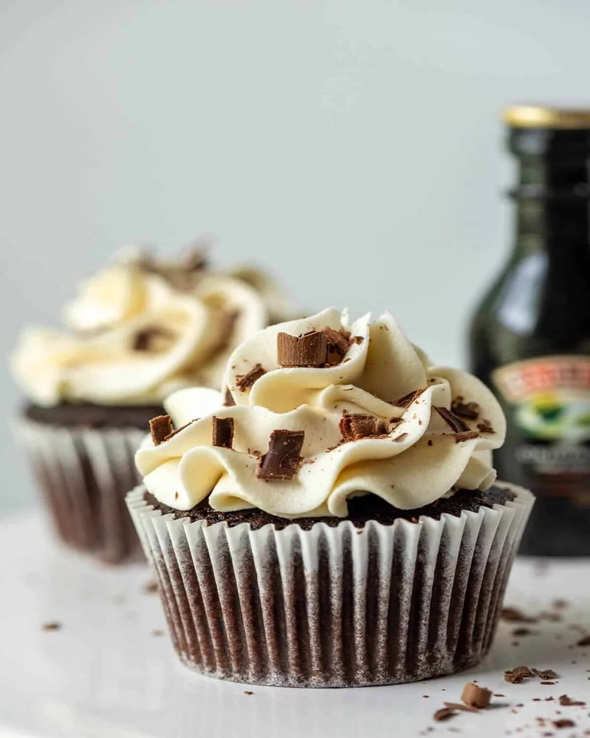 High-end vertical shot of a chocolate cupcake with white frosting and a Bailey's Irish Cream pipette.