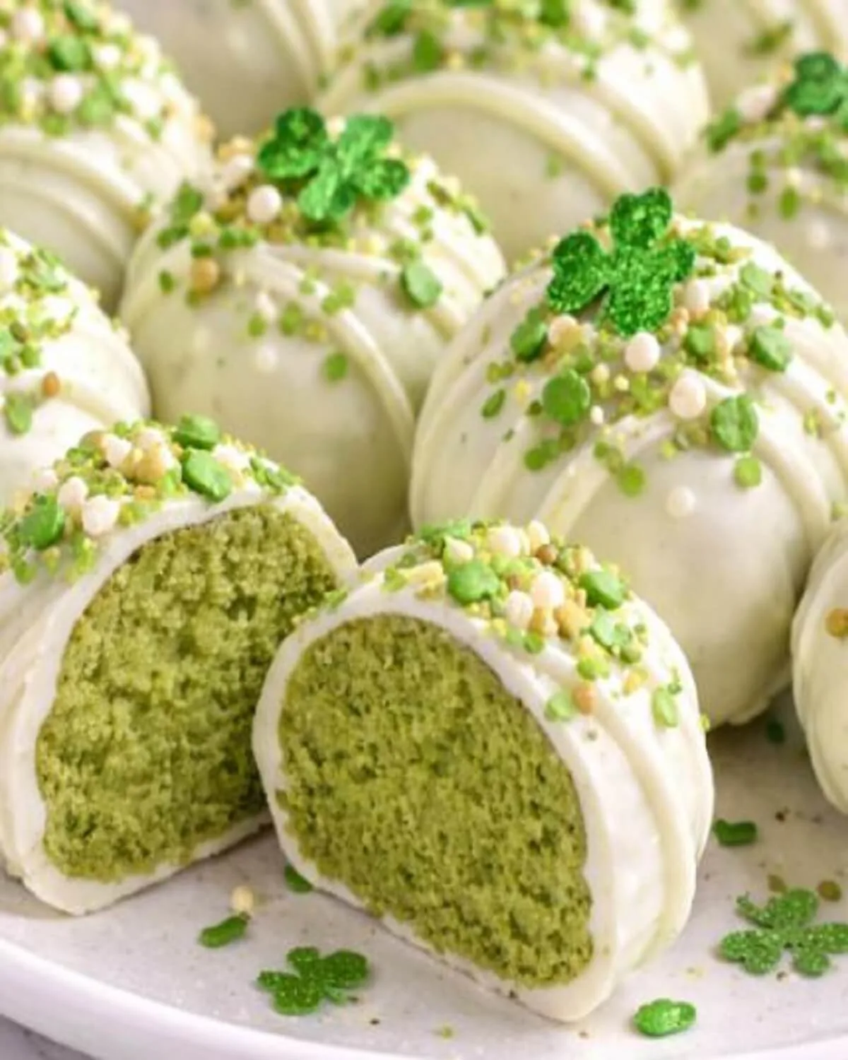 Vertical close-up of green matcha truffles served in a crystal coupe glass on a neutral background.