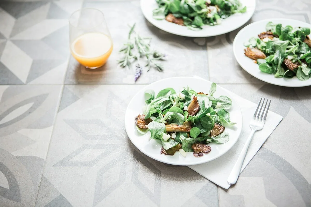 Three green salad dishes beside a clear drinking glass cup for easy Spring hosting ideas.